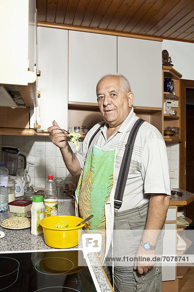 Älterer Mann in der Küche bereitet Salat zu