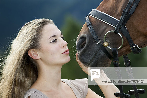 Junge Frau schmust mit Pferd  Oldenburger  Brauner  Nordtirol  Österreich  Europa