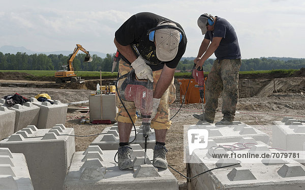 Bauarbeiter bohren Löcher in Steinblöcke  die anschließend f¸r eine Baugrund-Probebelastung verwendet werden sollen  auf einer Baustelle in Fridolfing  Bayern  Deutschland  Europa