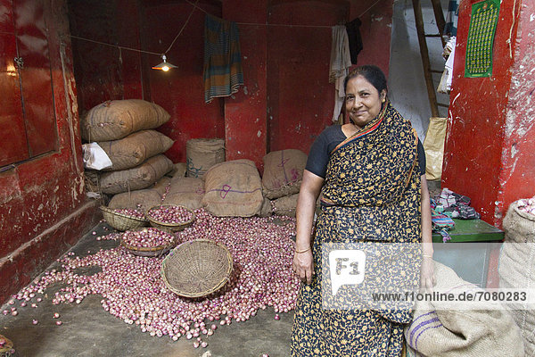 Marktfrau steht vor ihrem Geschäft  Zwiebeln und Jutesäcke dahinter  Gew¸rzmarkt  Old Dhaka  Dhaka  Bangladesch  S¸dasien