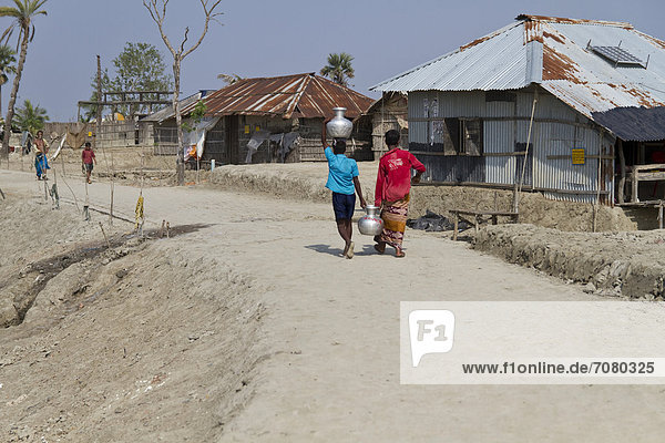 Zwei Jungen tragen Trinkwasser in Blechtöpfen  Zyklon Aila ¸berflutete 2009 den Ort Gabura  das Land ist seitdem versalzen  Anwohner sind abhängig von Trinkwasserlieferungen  Gabura  Sundabarns  Khulna District  Bangladesch  S¸dasien