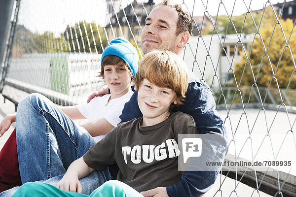 Vater und zwei Söhne auf einem Sportplatz