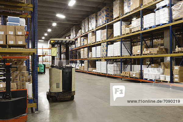 The interior of a storage unit or warehouse of a Correctional Facility. Shelves stacked high with goods ande supplies. A forklift truck.