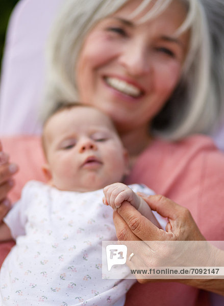Woman with grandchild sitting in lawn chair,  smiling