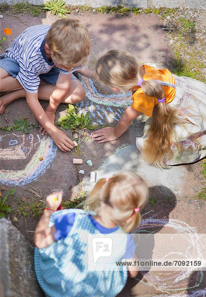 Deutschland Bayern Gruppe von Kindern die mit Kreide auf dem Gehweg zeichnen