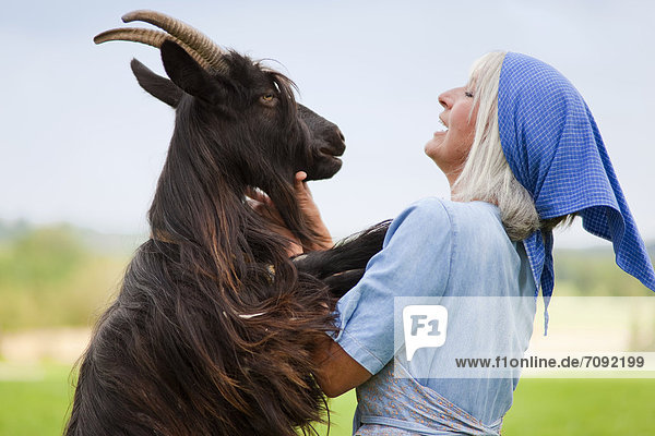 Mature woman with goat on farm