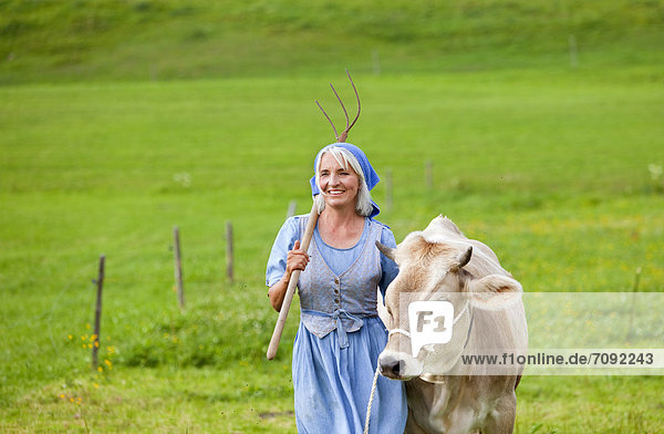 Reife Frau mit Kuh auf dem Bauernhof