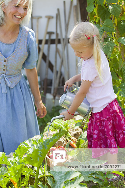 Mature woman and girl in graden caring for plants