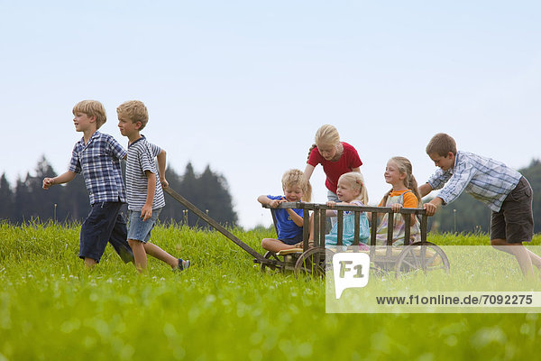 Germany  Bavaria  Group of children playing with hand cart