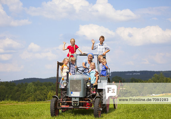 Woman with group of children sitting in old tractor