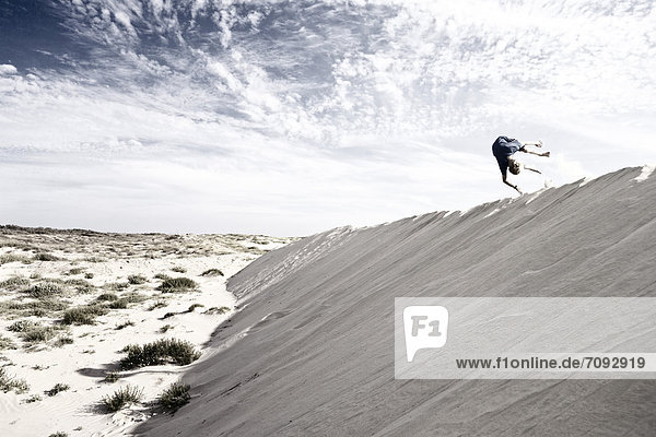 France  Boy jumping on sand dune