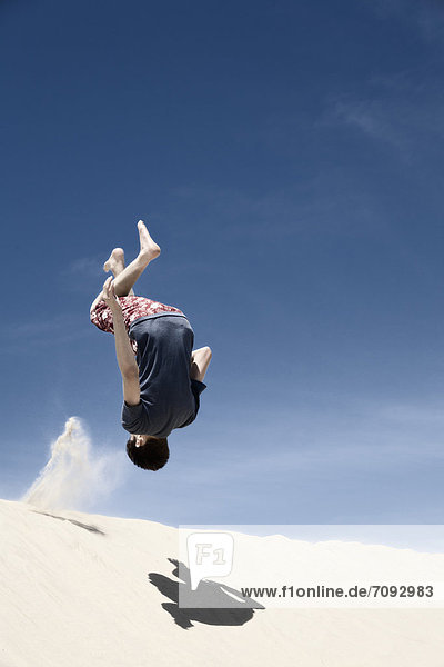 France  Teenage boy jumping on sand dune