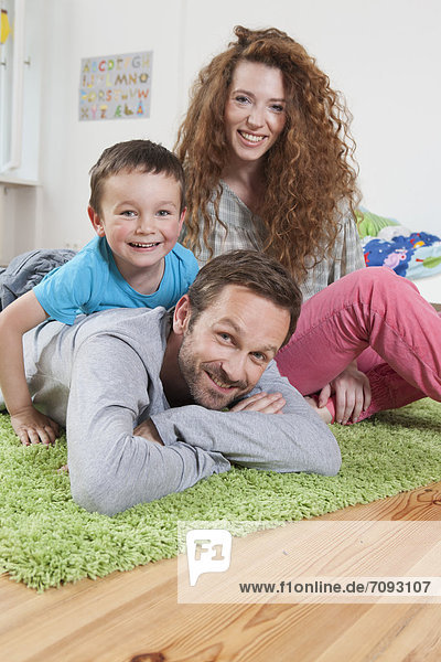 Germany Berlin Family lying on floor smiling portrait