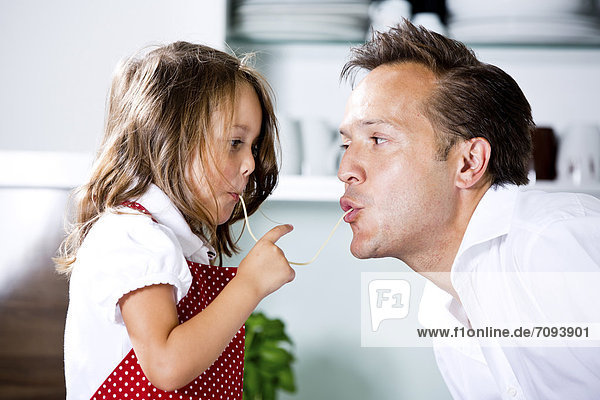 Germany  Daughter eating noodles with father in kitchen