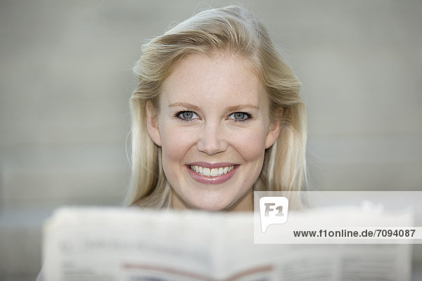 Europe  Germany  North Rhine Westphalia  Duesseldorf  Young woman with newspaper  smiling  portrait