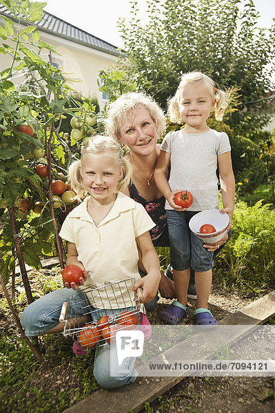 Deutschland  Bayern  Großmutter mit Kindern im Gemüsegarten
