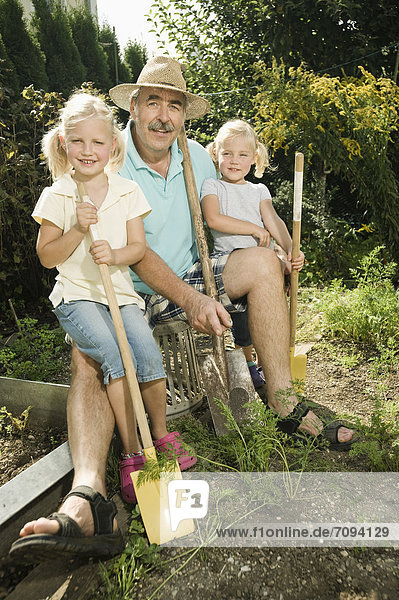 Germany  Bavaria  Grandfather with children in vegetable garden  smiling  portrait