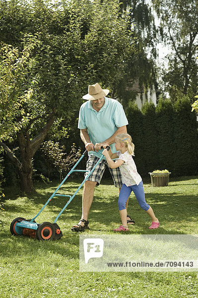 Germany  Bavaria  Grandfather with children mowing lawn