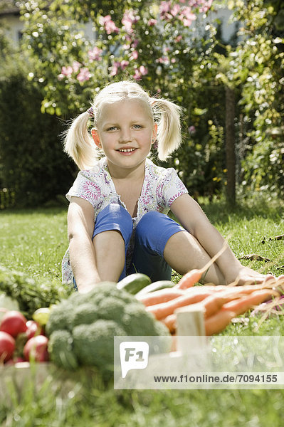 Mädchen sitzend in Gemüse-Gaeden  lächelnd  Portrait