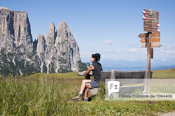 Italien  Mittlere erwachsene Frau sitzt auf der Bank und schaut zu Schlern in Südtirol.