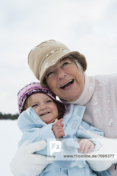 Großmutter und Kleinkind im Schnee umarmend