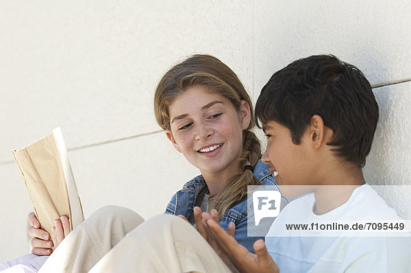 Preteen girl and boy sitting together outdoors