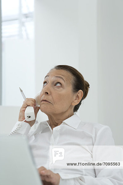 Senior businesswoman talking on landline phone