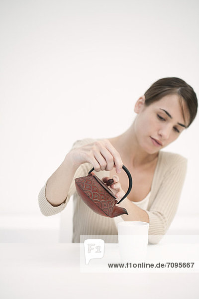 Frau schüttet eine Tasse Tee aus
