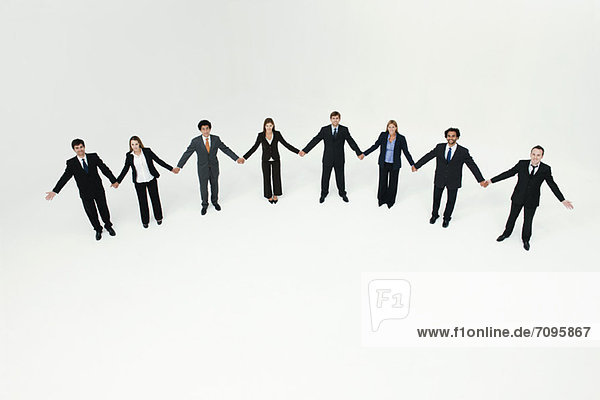 Businessmen and businesswomen standing together holding hands