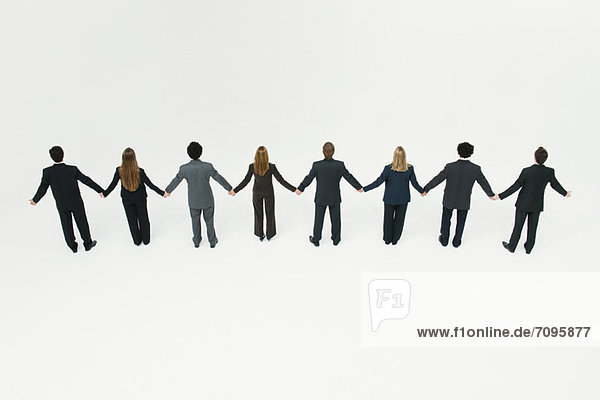 Geschäftsmänner und Geschäftsfrauen stehen zusammen und halten Händchen.