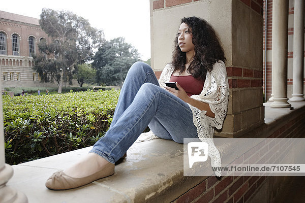 Mixed race student sitting on campus
