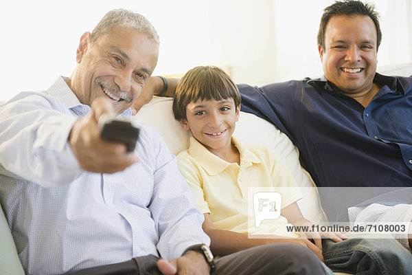 Hispanic grandfather  father and son watching television