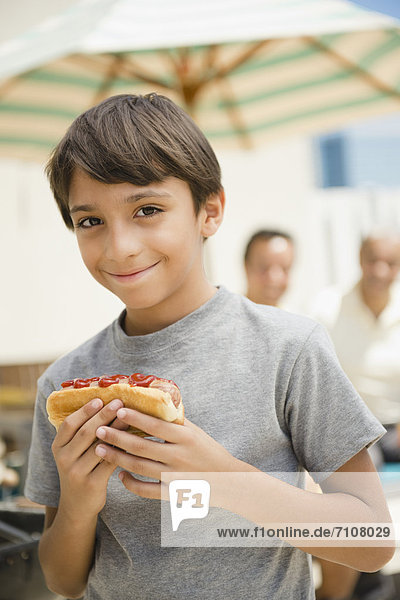 Hispanic boy eating hot dog