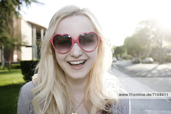 Smiling Caucasian woman in heart-shaped sunglasses