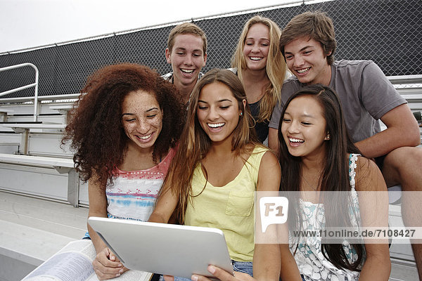sitzend  Zusammenhalt  benutzen  Freundschaft  Schule  Tablet PC  unüberdachte Tribüne