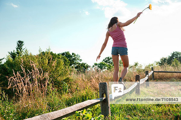 Teenage girl balancing on wooden fence