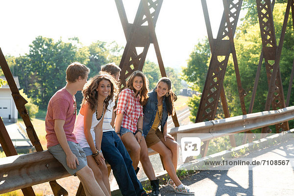 Gruppe von Freunden auf der Brücke sitzend