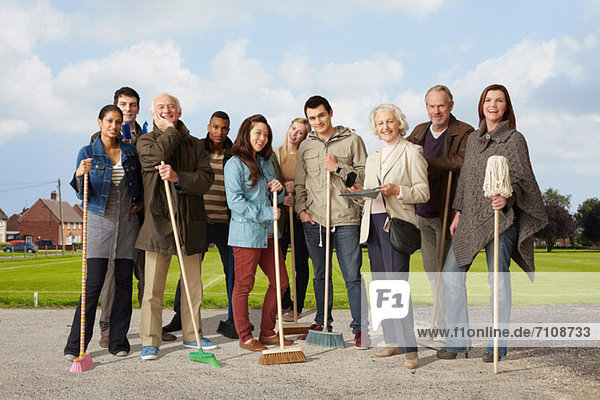 Group of people standing with brooms and mop