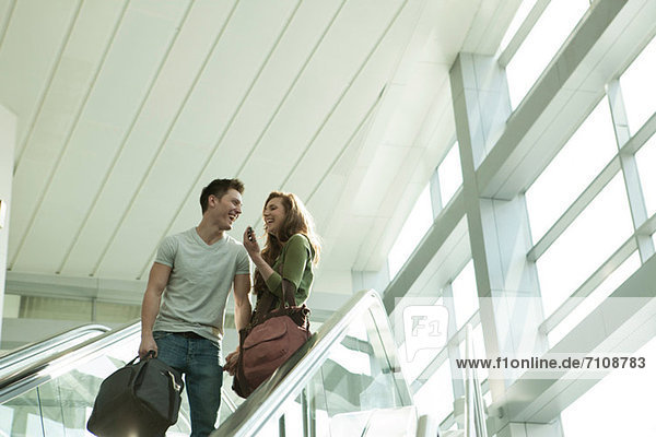 Junges Paar auf der Rolltreppe unterwegs