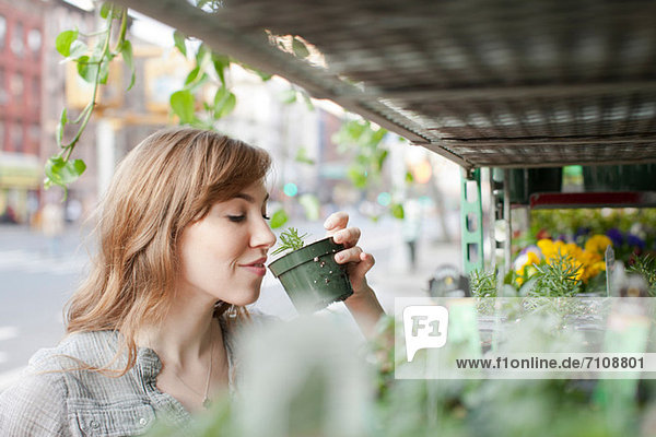 Junge Frau riecht eine Pflanze