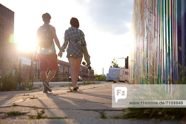 Young couple walking holding hands  rear view