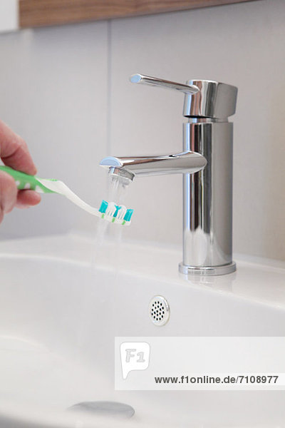 Fließendes Wasser auf die Zahnbürste im Waschbecken