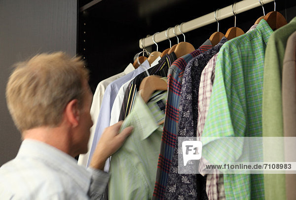 Mann nimmt Hemd aus der Garderobe