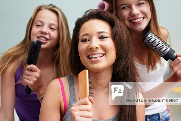 Teenage girls singing into hairbrushes
