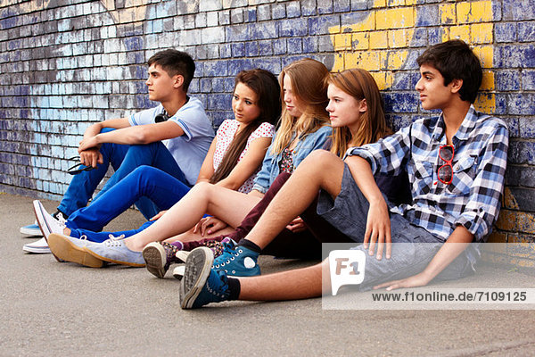 Teenagers sitting against a wall