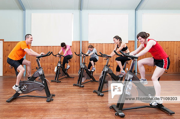 Male instructor leading female spinning class