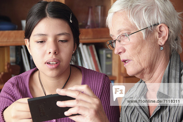 Teenager erklärt einer Seniorin ein iPad
