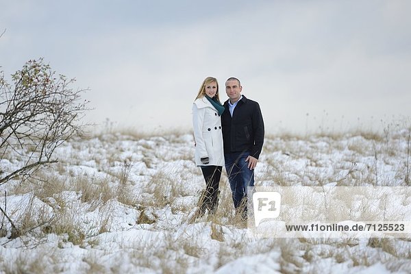 Couple standing on snowcapped meadow