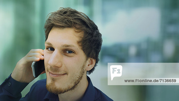 Portrait of a young man with a beard making a telephone call  smiling  relaxed