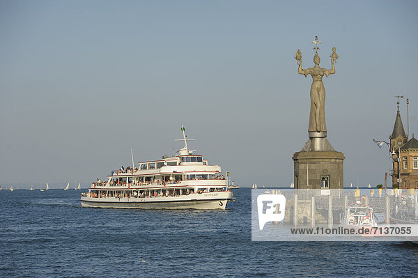 Ship entering the Lake Constance harbour entrance with the Imperia statue by sculptor Peter Lenk Konstanz Baden-Wuerttemberg Germany Europe
